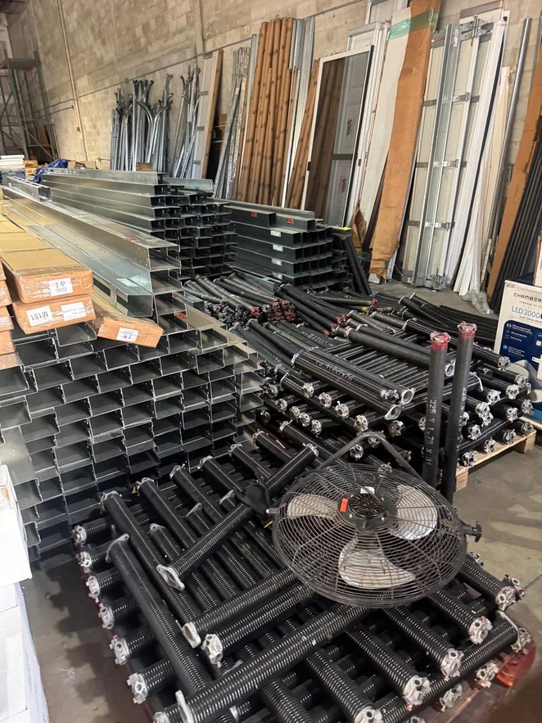 Stacks of steel tracks, shafts and packaged hardware in a workshop