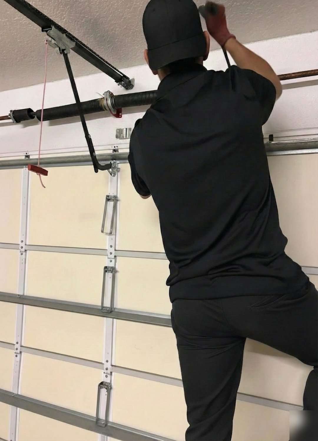 Worker reaching up to fasten hardware above a closed garage door