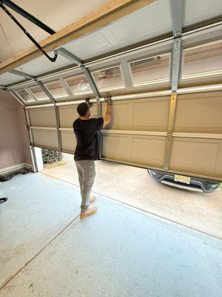 Worker standing under a raised door and checking an overhead component