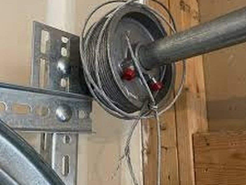 Close view of a lift cable wound around a metal drum beside its bracket