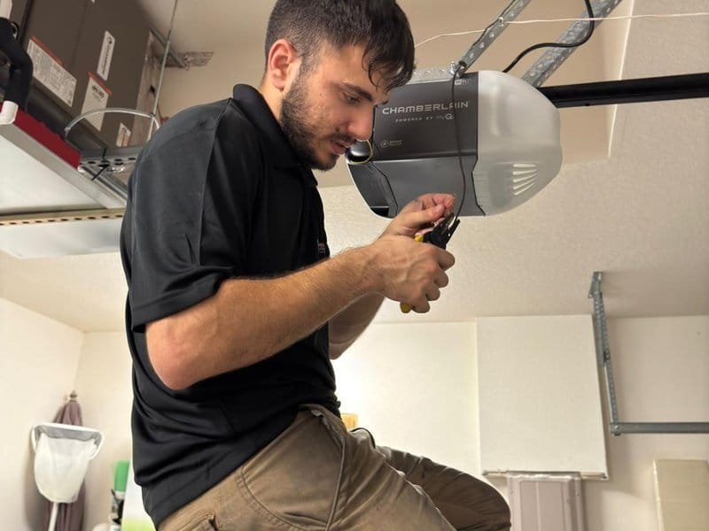 Worker looking closely at wiring on an overhead garage door opener